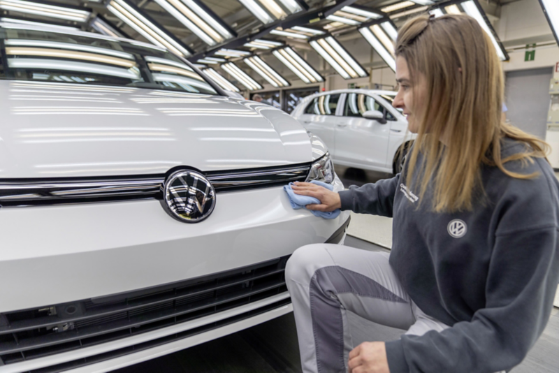 Young woman from Volkswagen quality assurance wiping a vehicle with a cloth