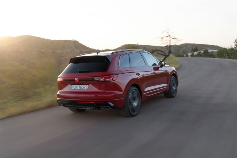 A VW Touareg Elegance eHybrid, diagonal view from the front, at a charging station in front of a modern house.