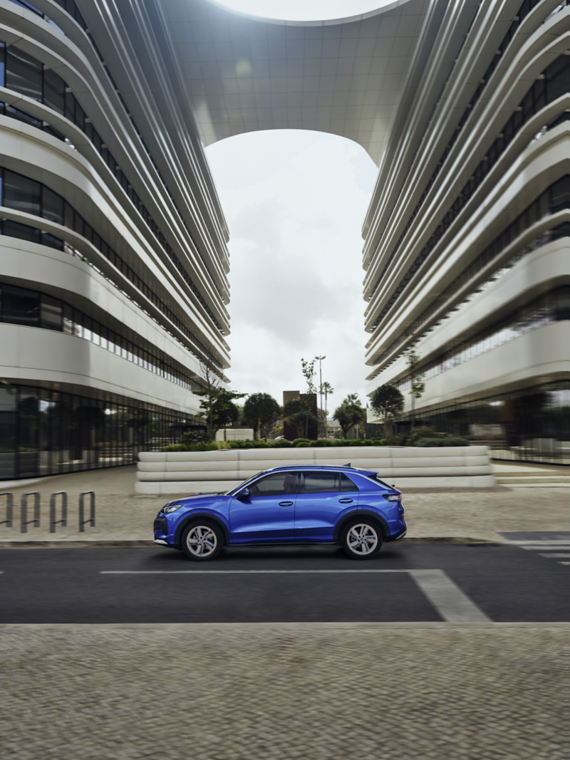 Blå Volkswagen T-Roc står parkerad vid en hög byggnad