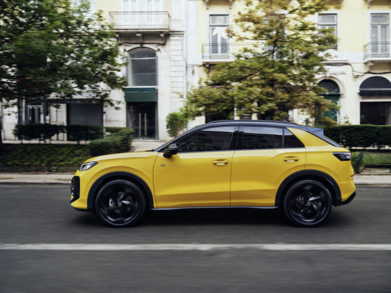 A red VW T-Roc Style stands in front of a modern building in sunlight.