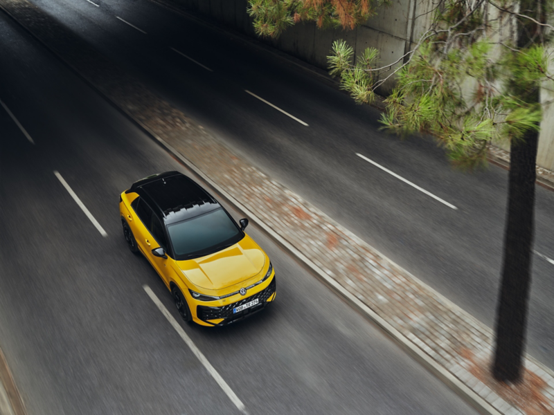 Gul Volkswagen kör på en väg.