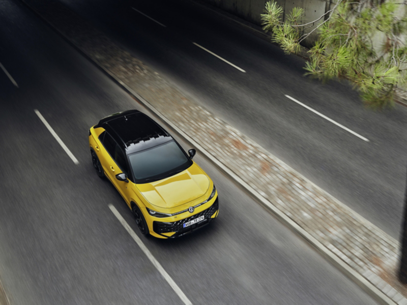 En gul Volkswagen T-Roc med svart tak, sedd snett ovanifrån, kör längs en väg