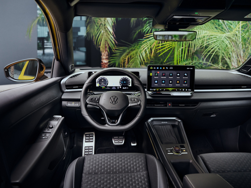 Interiören i nya T-Roc där ratten, mittkonsollen och infotainmentsystemet syns. Gröna palmblad utanför framrutan