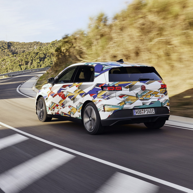 En kamouflerad ID. Polo kör längs väg, sedd snett bakifrån