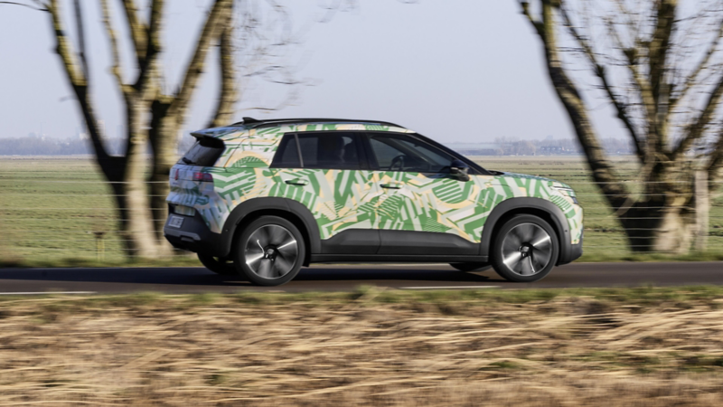 Profilansicht eines fahrenden VW ID. Cross mit Konzeptbeklebung auf einer Landstrasse.