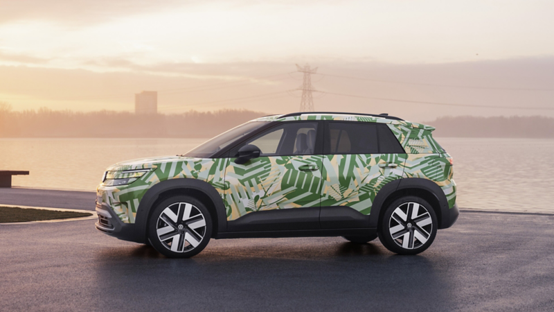 Ein VW ID. Cross mit grüner Camouflage-Beklebung steht seitlich an einem Hafenanleger