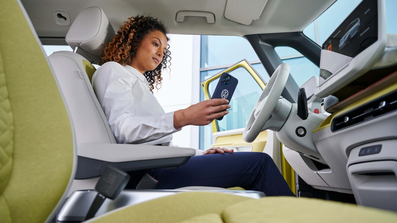 A woman sitting in the cockpit of an ID. Buzz while using her smartphone. 