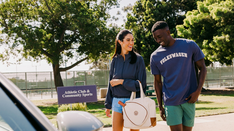 A couple walking toward a Volkswagen vehicle wearing athletic clothing.