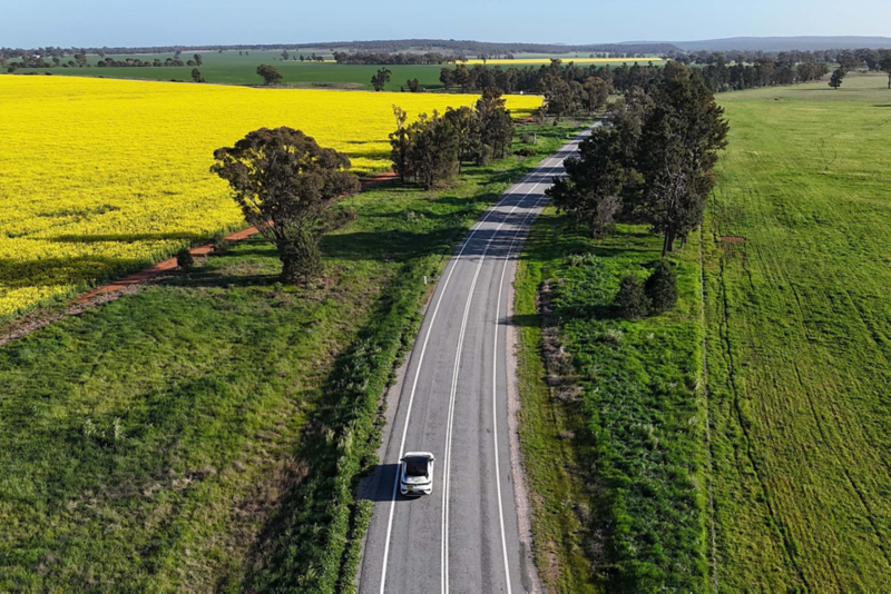 Ariel shot of ID.4 driving down a road with fields either side