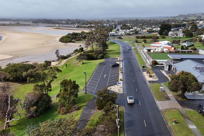 ID.4 driving on road with houses to the right and beach to the left