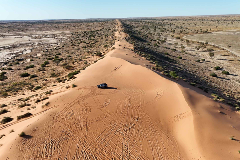 Ariel view of desert landscape and Amarok, with tire marks in the sandy terrain
