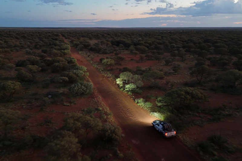 VW Amarok driving at sunset with lights on in desert
