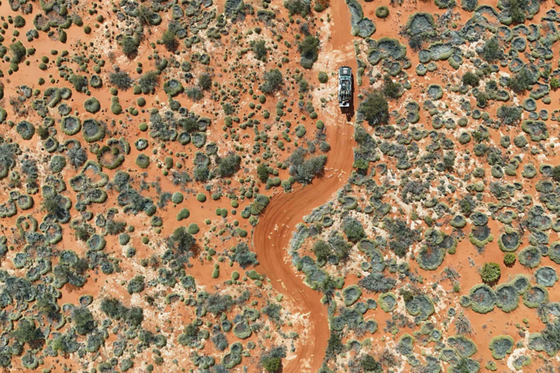 Ariel view of Amarok driving through winding desert dirt track with shrub land either side