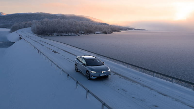 En ID.7 Tourer kör över en bro i ett vinterlandskap