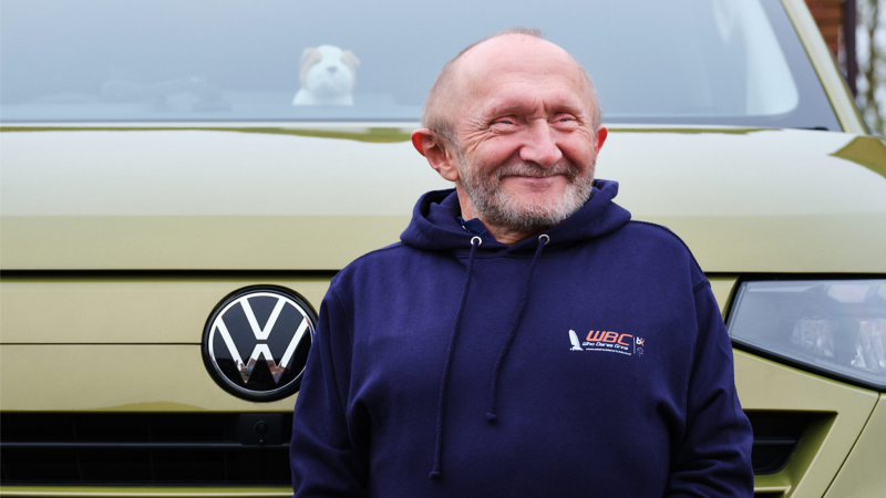 A smiling man standing in front of a VW e-Transporter Kombi van