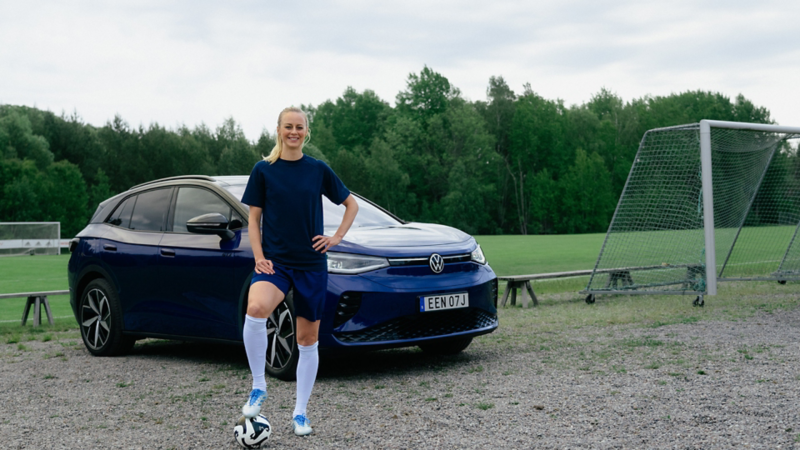 Amanda Ilestedt poserar med en fotboll framför en blå VW ID.4