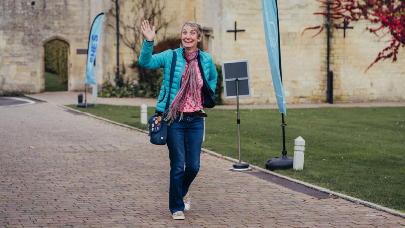 A smiling woman waving at the camera