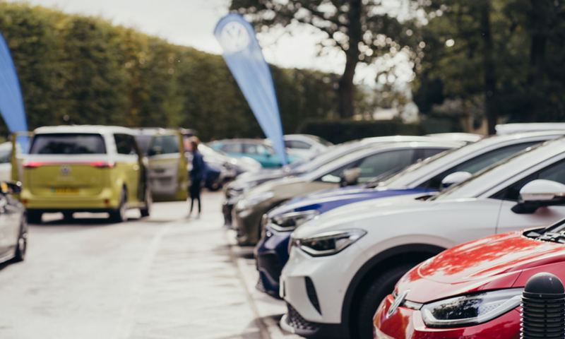 A line-up of electric VW vehicles in a car park on a sunny day