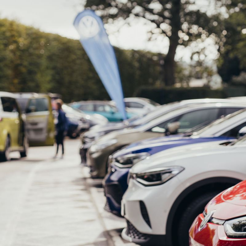 A line-up of electric VW vehicles in a car park on a sunny day