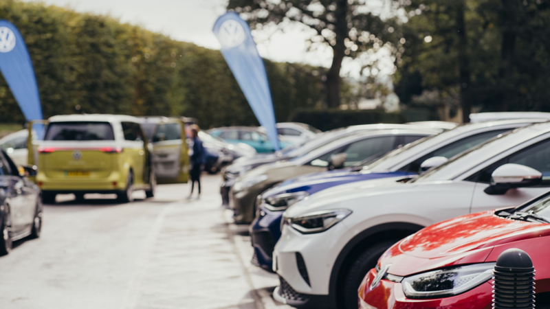 A line-up of electric VW vehicles in a car park on a sunny day