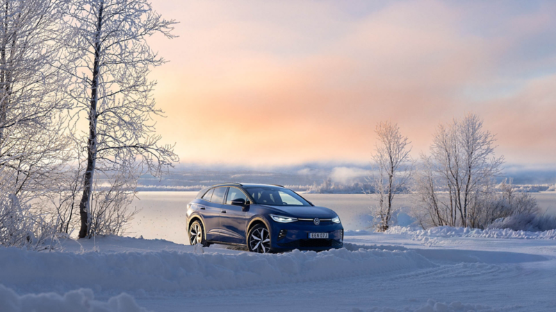 En blå VW ID.4 står parkerad i ett vinterlandskap
