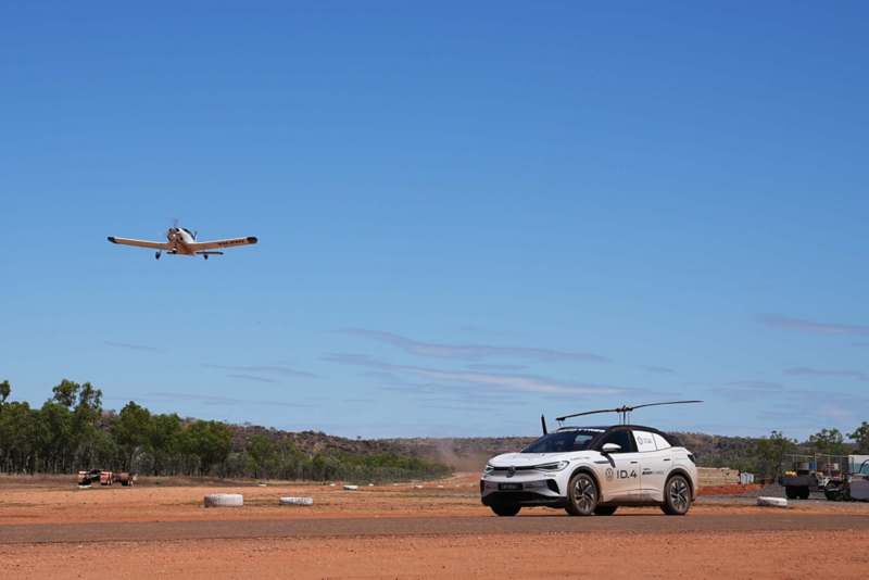 VW ID.4 driving through red desert with plane in background