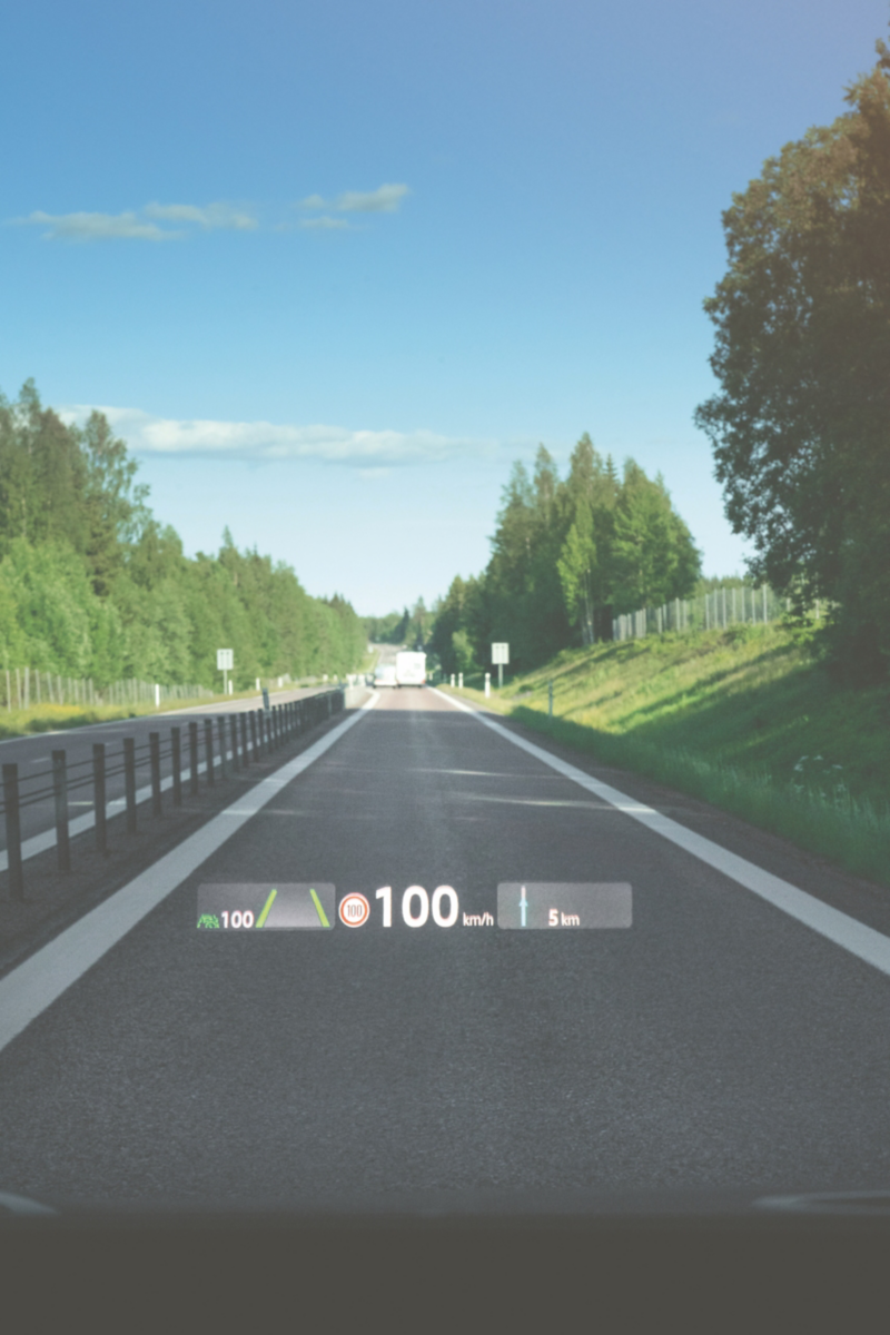 Landsväg sedd från förarplats med head-up-display som visar hastighet och vägmarkeringar