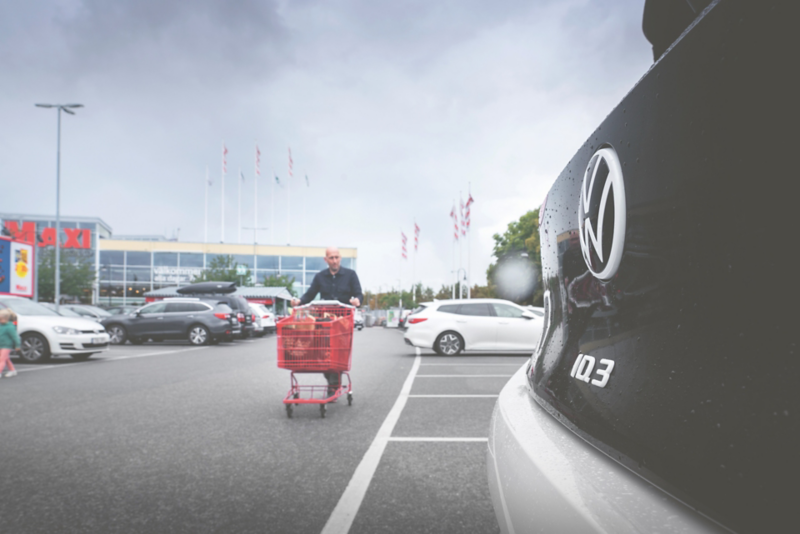 Närbild på Volkswagen ID.3 bakdel på en parkering utanför Ica Maxi, i bakgrunden går en person med kundvagn mot bilen