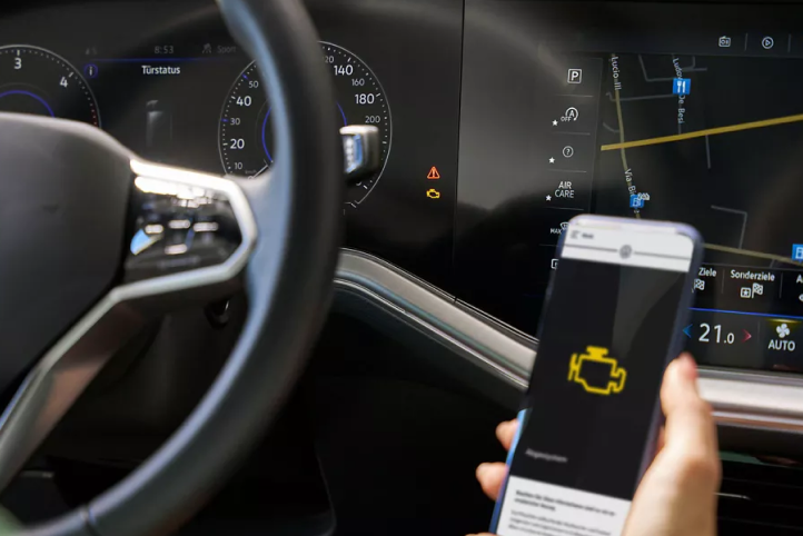 Un teléfono móvil sostenido frente al interior de un vehículo VW, mostrando la luz del tablero en la pantalla.