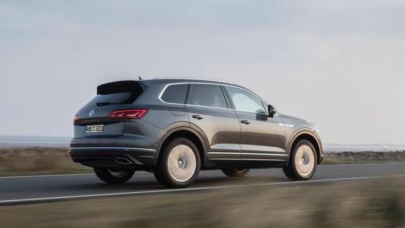 Pareja con el Volkswagen Touareg en la entrada de una casa