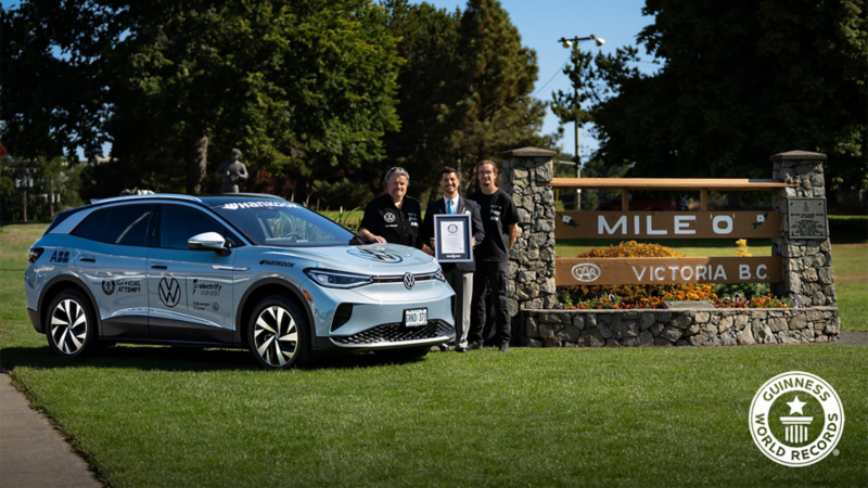 3 people standing next to the VW ID.4, with the person in the middle holding a Guiness World Record certificate.