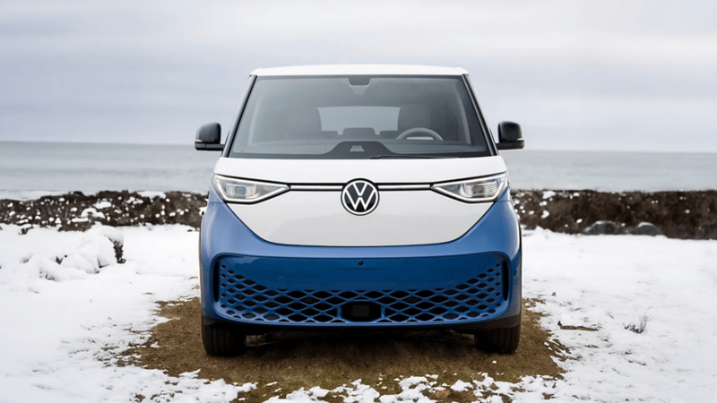 Front view of a blue and white VW ID. Buzz parked on snowy ground near water.