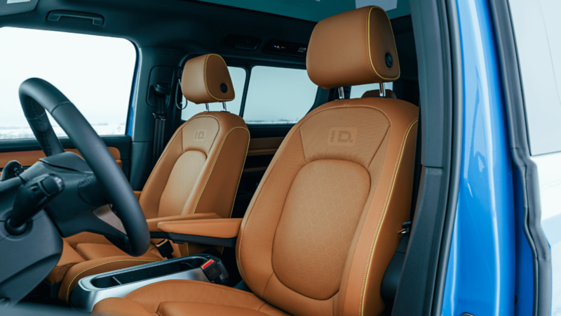 Interior view of a car with light brown leather front seats, yellow stitching, and "ID." embossed on the headrests.