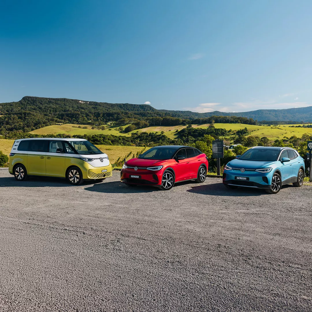 VW EVs parked in front of rolling farmland