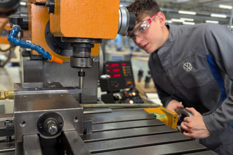 Auszubildender in Schutzkleidung betätigt eine Maschine zum Fräsen