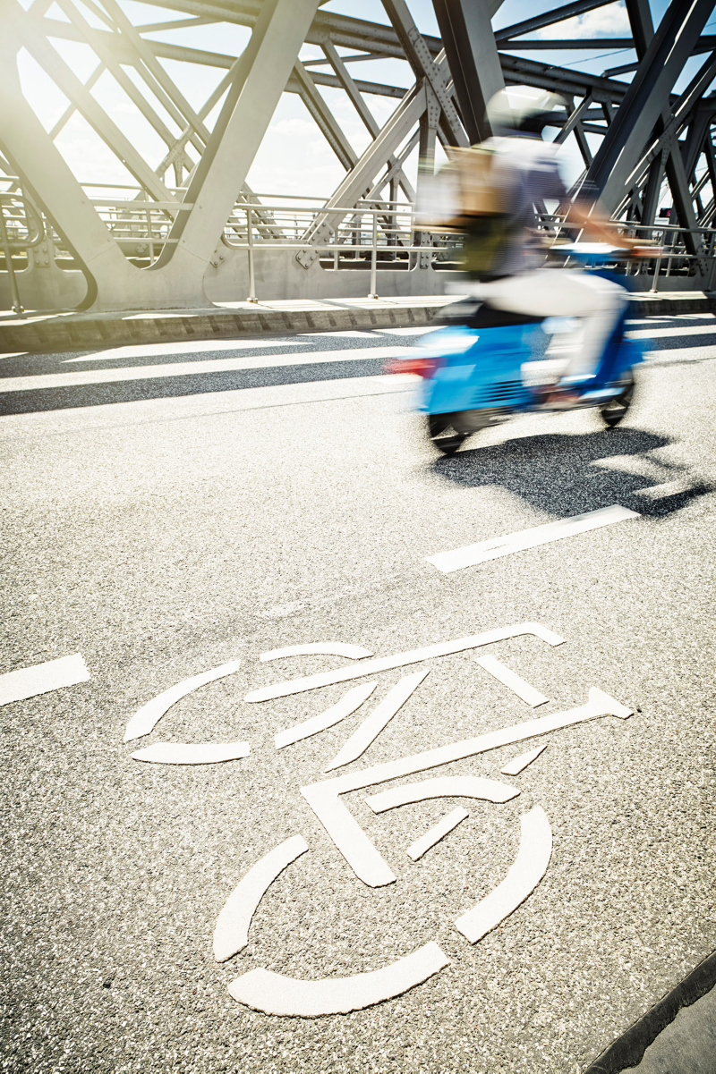 Man riding a scooter from the side, with the scooter motion-blurred to convey a sense of speed and dynamism