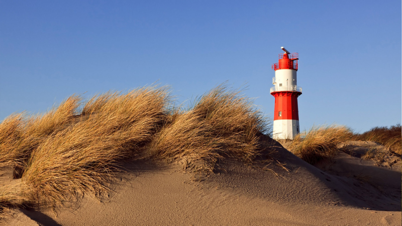 View of the lighthouse on the island of Borkum with dunes in the foreground