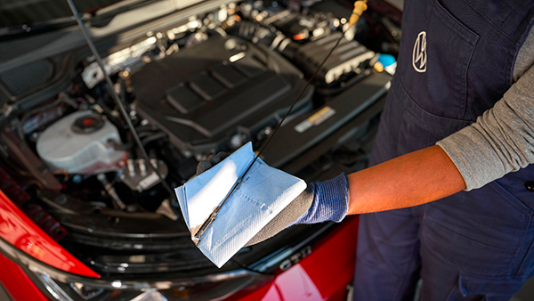 Inquadratura di un meccanico Volkswagen controllare il livello dell'olio della vettura.