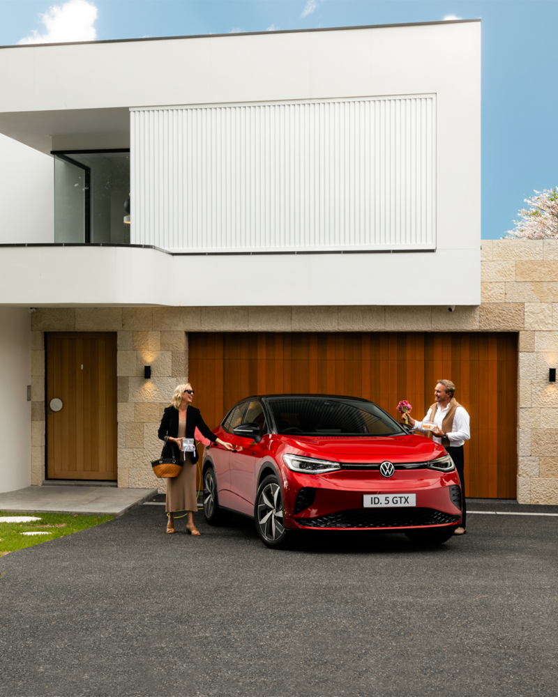 Couple getting into red VW car parked outside house
