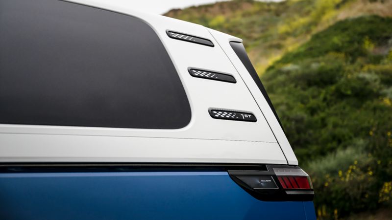 Side air vents on the rear of a 2025 Volkswagen ID. Buzz with a hillside in the background.