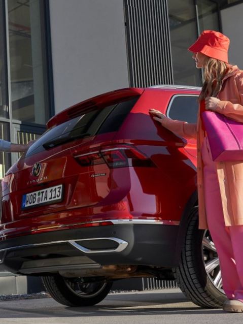 Two people standing behind a red VW Touareg