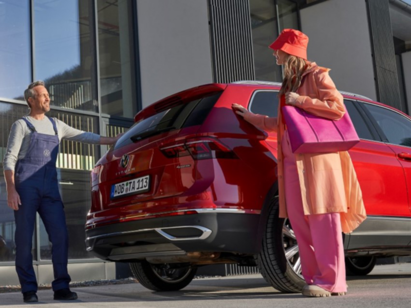 Two people standing behind a red VW Touareg