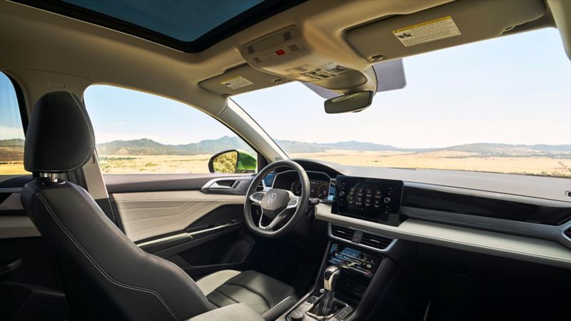 The interior of the 2025 Taos, view of the steering wheel and infotainment system from the rear seats.