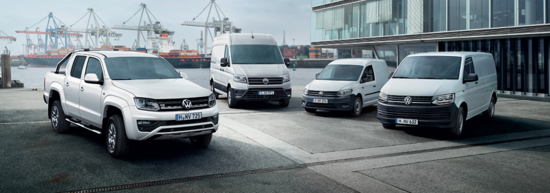 Volkswagen commercial vehicles parked together, including a white van, a white truck, and a white SUV.