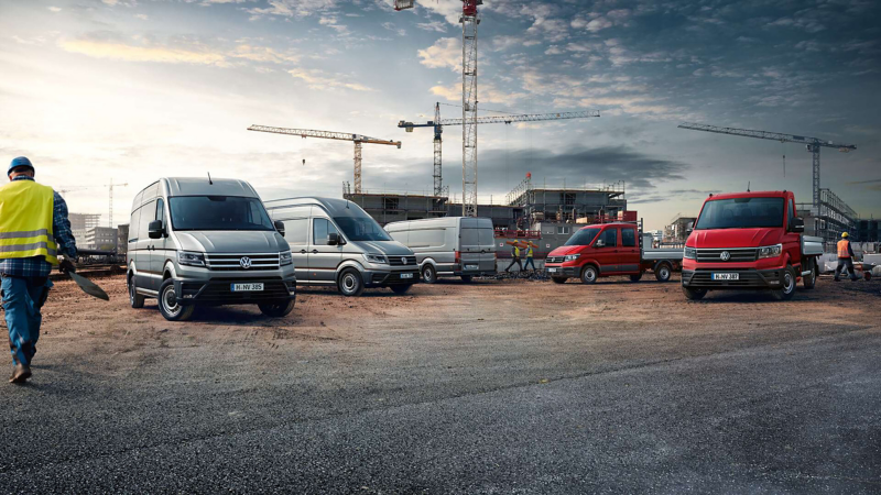 Volkswagen commercial vehicles parked together, including a white van, a white truck, and a red SUV.