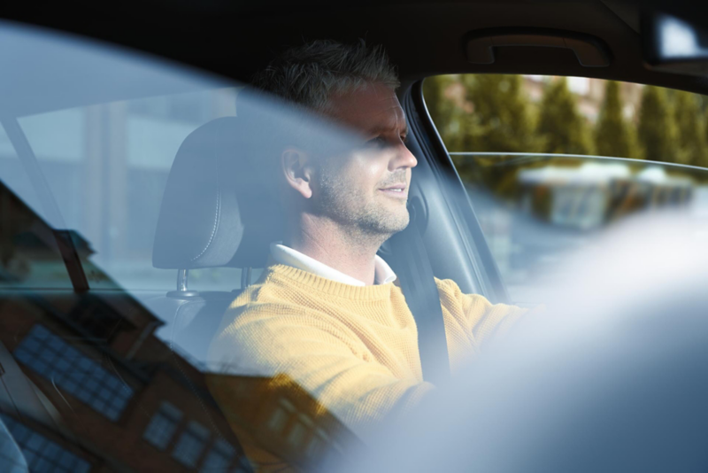 Uomo con pullover giallo alla guida di una Volkswagen