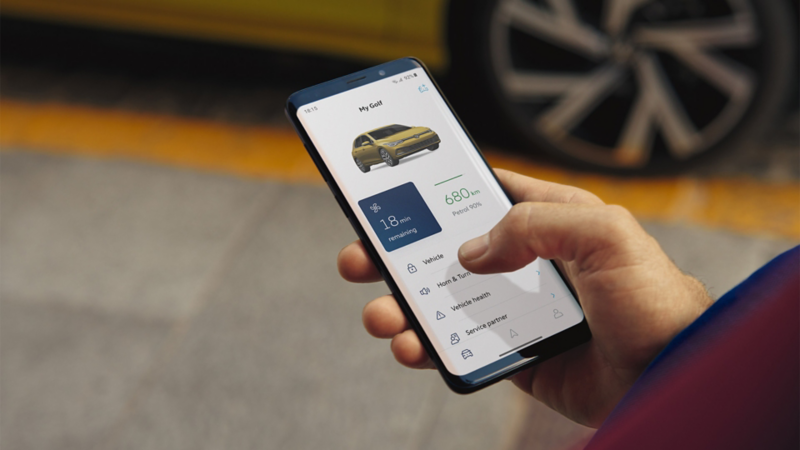 Une personne tient un smartphone dans sa main. Sur l’écran, on peut voir les données actuelles du véhicule.