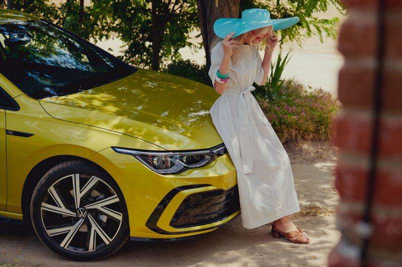 Une femme en robe blanche contre le capot de la nouvelle Golf