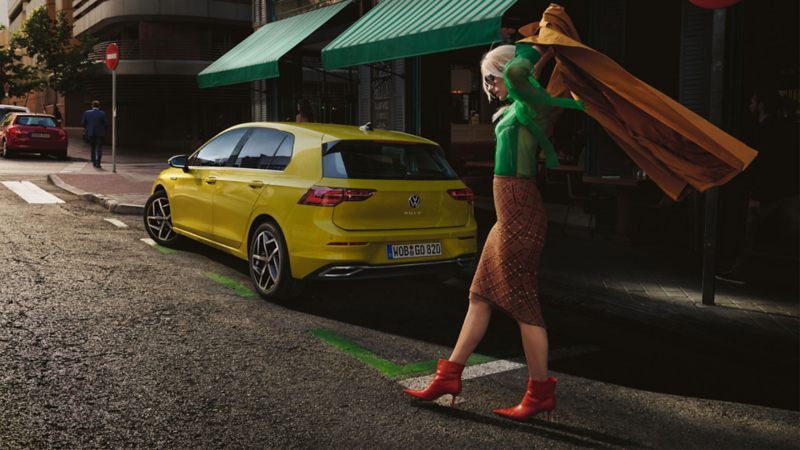 Der neue Golf und eine Frau läuft hinten durch