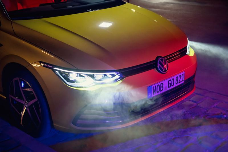 Close-up of the headlight of a yellow VW Golf. The optional IQ.Light is activated.